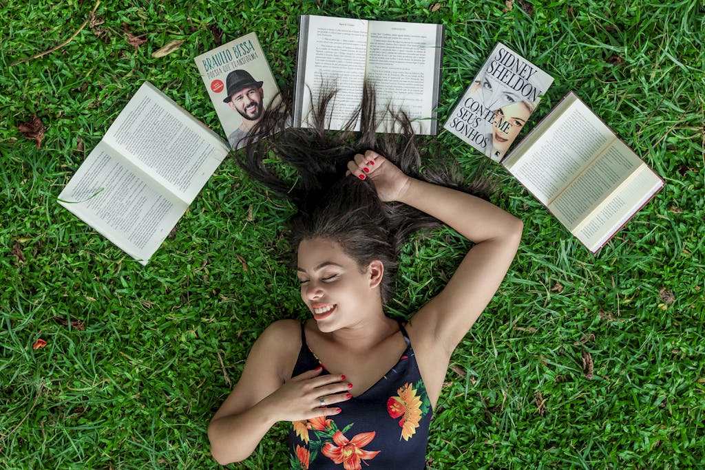 Woman Lying Down on Grass Beside Opened Books